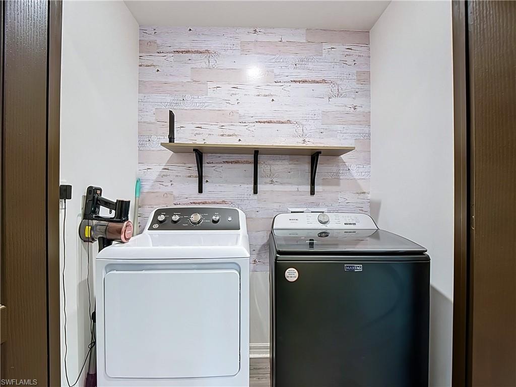 Dedicated laundry area featuring a wood-look accent wall
