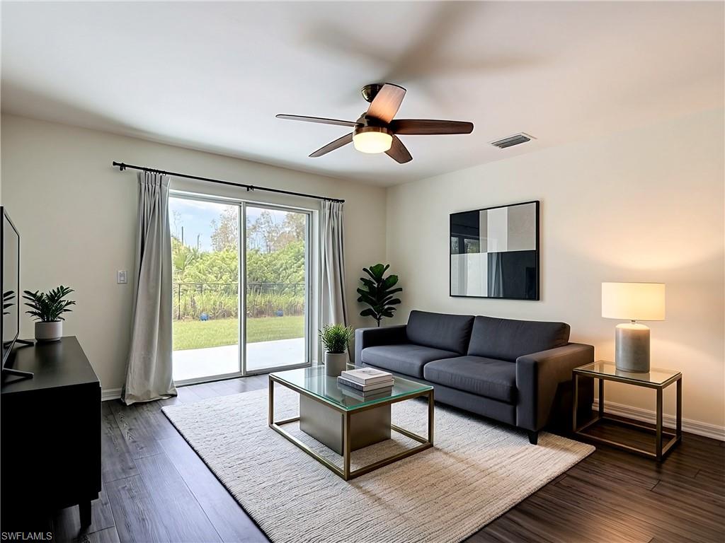 Spacious interior featuring wood-finish flooring, a contemporary ceiling fan with integrated lighting, and a sliding glass door providing natural light and exterior access to a patio