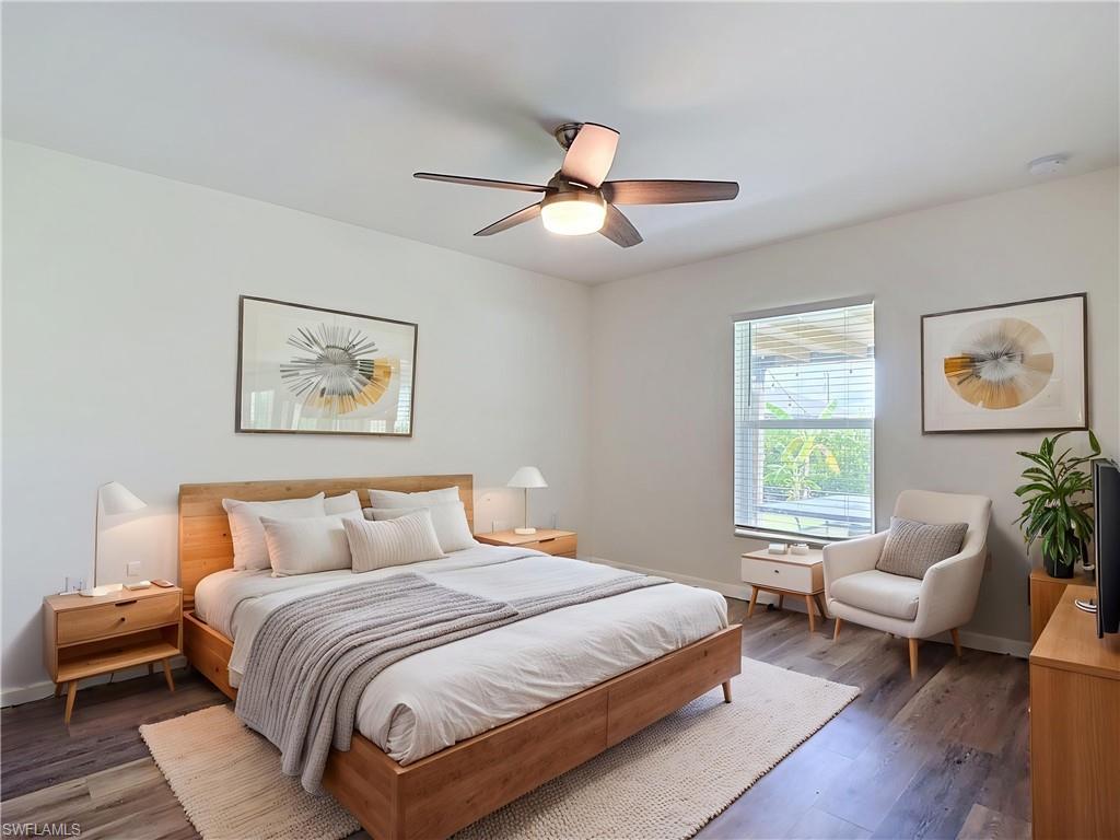 Spacious interior featuring wood-finish flooring, a ceiling fan with integrated lighting, a large window with blinds, and light-toned walls