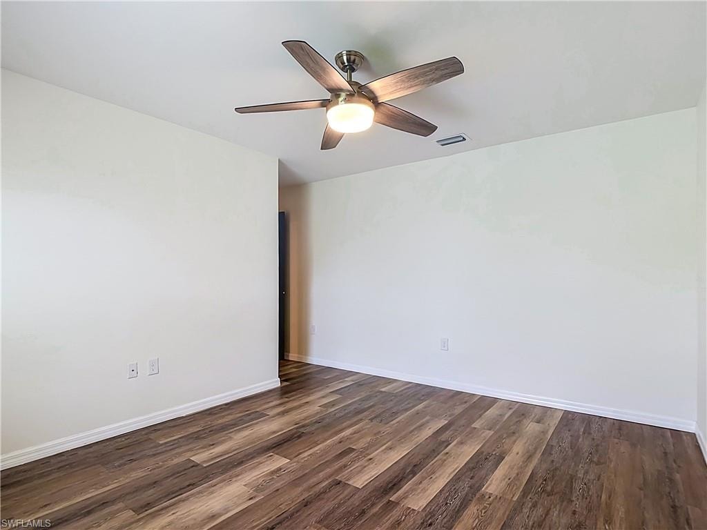 Spacious room featuring wood-finish flooring, white baseboards, and a ceiling fan with integrated lighting