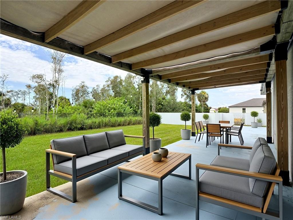 Expansive outdoor patio featuring a slatted wood pergola with a retractable fabric canopy