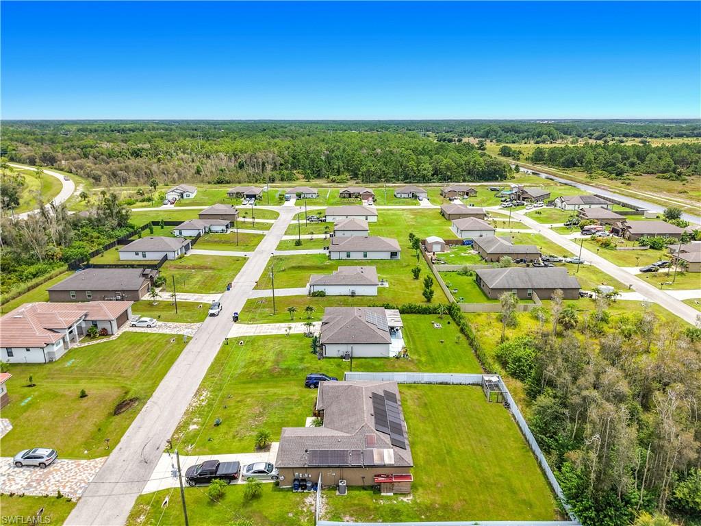 Expansive aerial view of a residential neighborhood featuring multiple single-story homes, paved roads, and lush green lawns