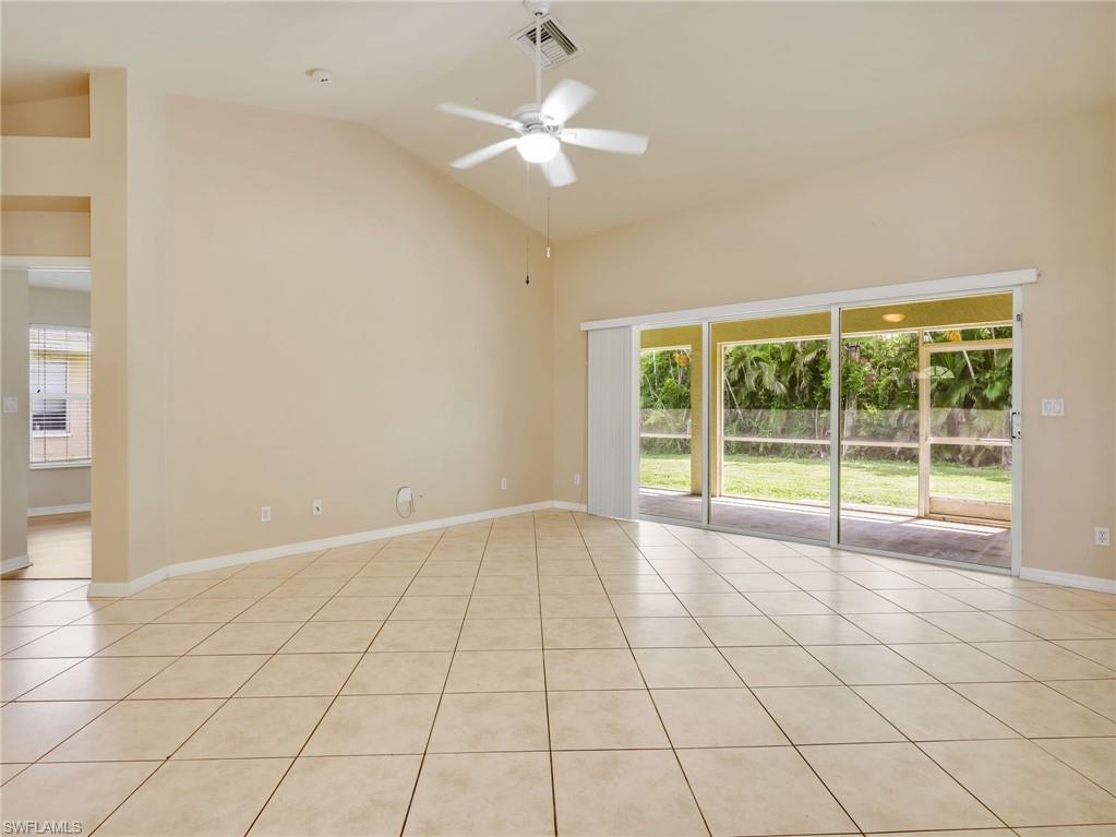 Living Room with Tile Flooring, Vaulted Ceiling, Sliders to the Screened In Lanai, & Ceiling Fan