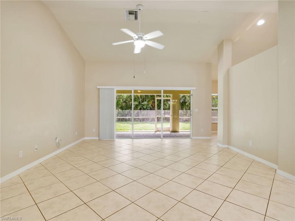 Living Room with Tile Flooring, Vaulted Ceiling, Sliders to the Screened In Lanai, & Ceiling Fan