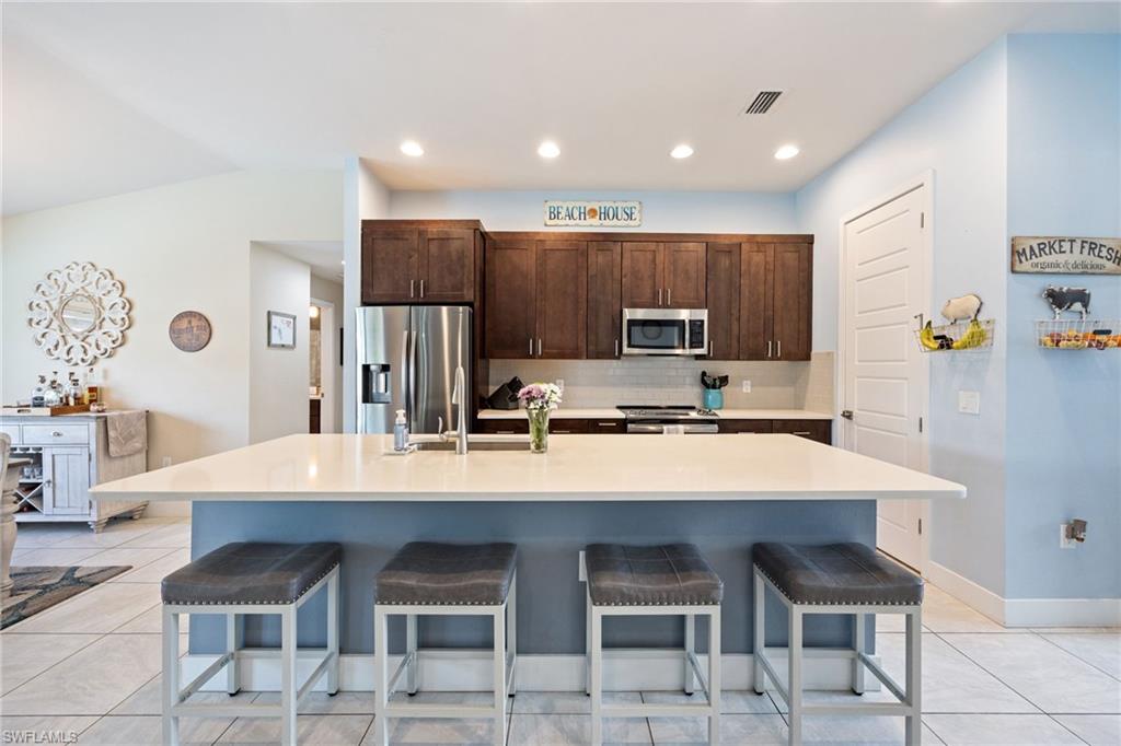Kitchen featuring a peninsula with countertop seating, stainless steel appliances, dark wood-finish cabinetry, and recessed lighting