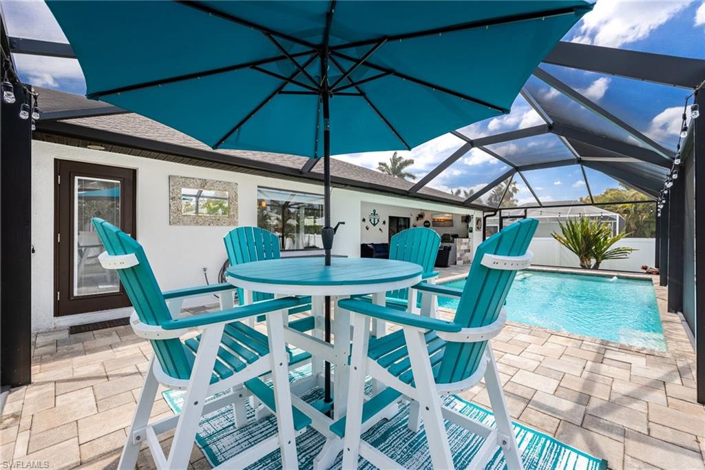 Screened-in pool area featuring a paver deck, a rectangular swimming pool, and a white stucco exterior with dark-framed windows and doors