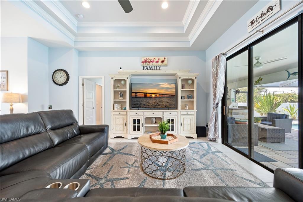 Spacious living area featuring a tray ceiling with recessed lighting and a ceiling fan