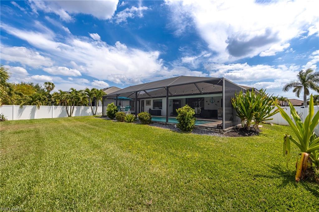 Expansive backyard featuring a screened-in pool enclosure, inground pool, and a white vinyl fence