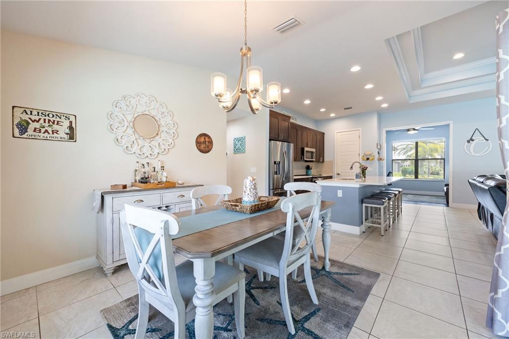 Open-concept living space featuring light tile flooring, a kitchen with dark wood-finish cabinetry, a center island with bar seating, and recessed lighting
