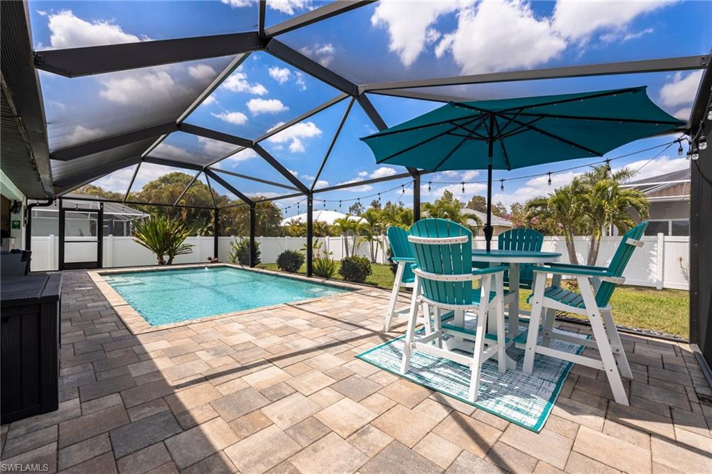 Screened outdoor living area featuring a swimming pool, paver patio, and string lighting