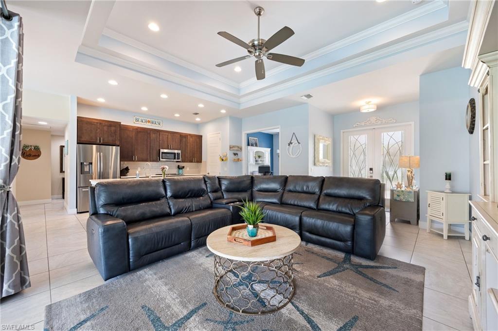 Open-concept living area featuring a tray ceiling with a ceiling fan, recessed lighting, and tile flooring
