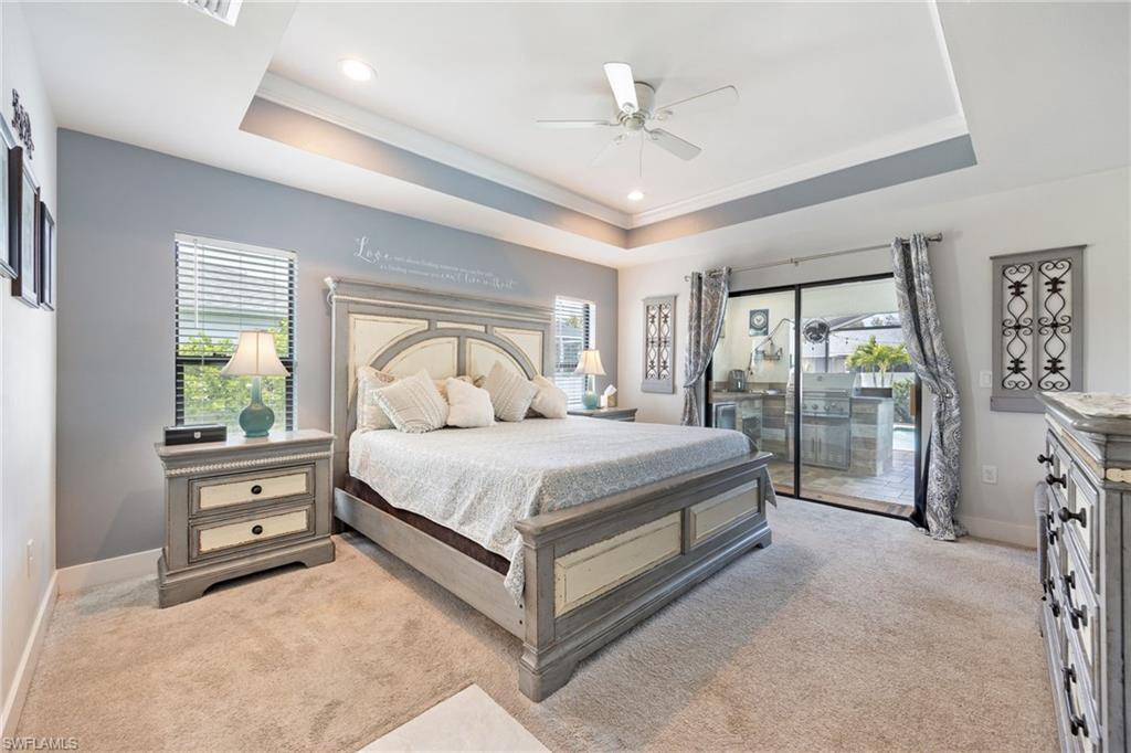 Tray ceiling with recessed lighting and a ceiling fan, plush carpet flooring, and a large sliding glass door with exterior access