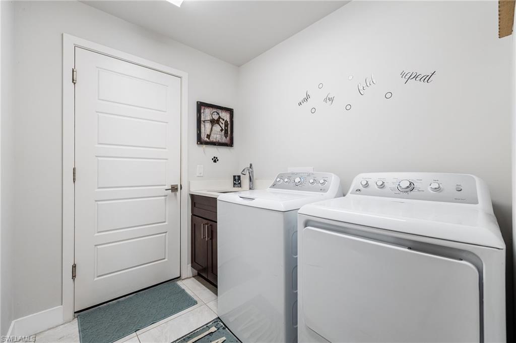Laundry area featuring a built-in sink with a countertop, dark wood-finish cabinetry, and light-toned tile flooring
