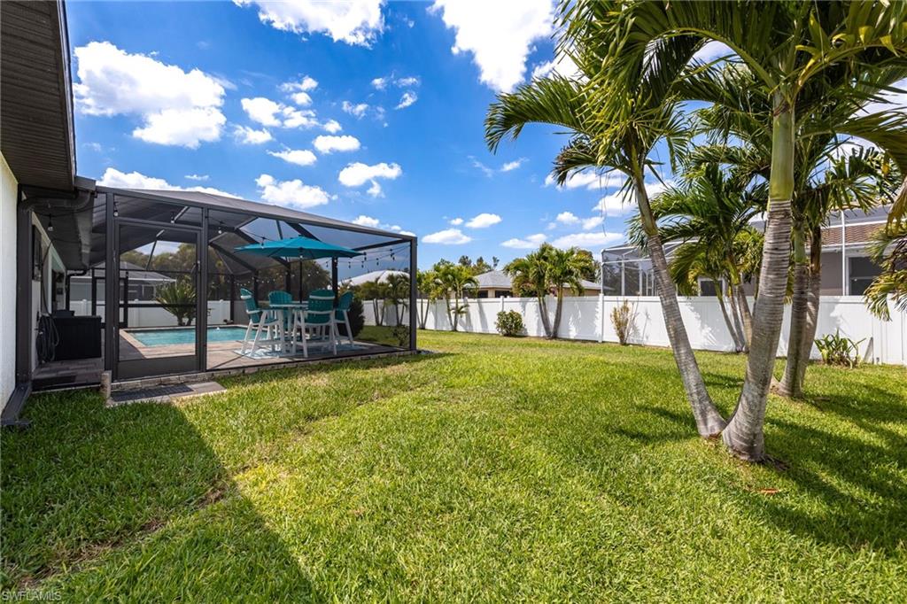 Expansive backyard featuring a screened-in patio, swimming pool, and mature palm trees