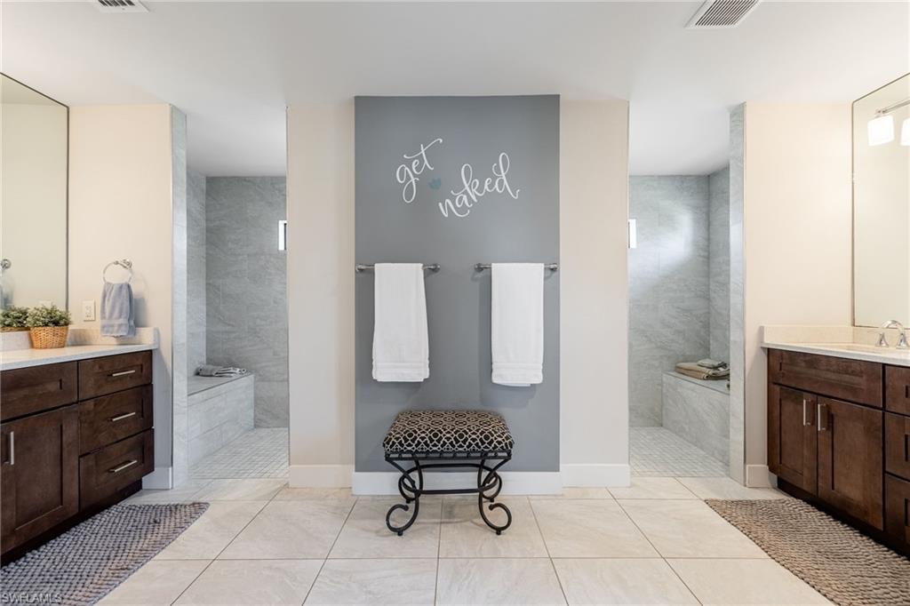 Dual vanity bathroom featuring light tile flooring and individual walk-in showers