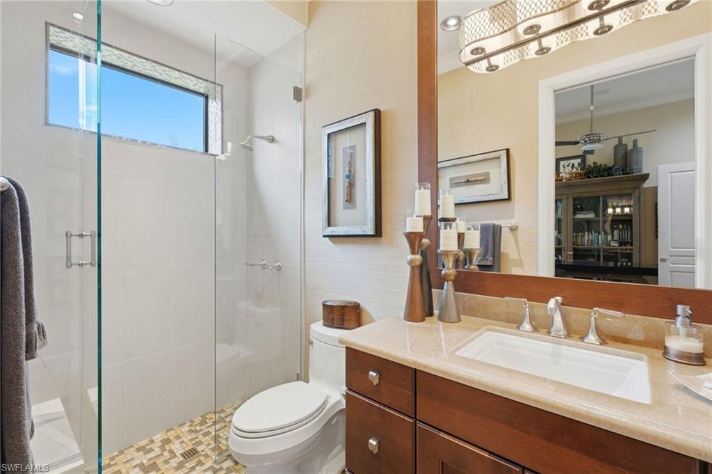 The fourth ensuite bath exudes refined elegance with luxurious marble flooring, a single marble-topped vanity, a walk-in shower with seamless glass enclosure, and sophisticated grasscloth wallpaper adding a touch of texture and warmth.