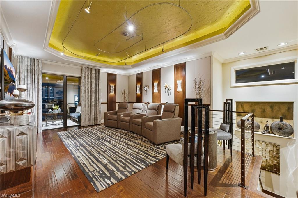 As you ascend to the second level, you’ll discover an exceptional theater room featuring rich wood flooring, sophisticated track lighting, multiple plush reclining seats, and dramatic uplighting accentuating the tray ceiling. Elegant suede wall coverings add warmth and refinement, while direct access to the private balcony completes this extraordinary entertainment retreat.