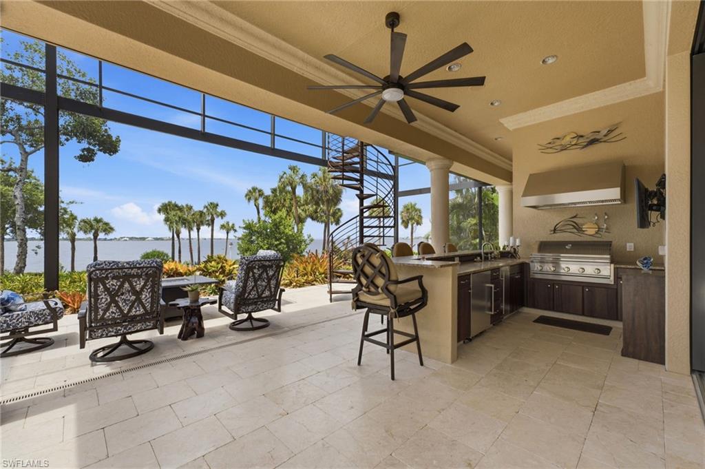 Your extraordinary outdoor living space is appointed with elegant tumbled travertine flooring and a fully equipped Somerset outdoor gas grill, sink, ice maker, refrigerator, and generous entertaining seating. Refined granite countertops elevate the space, while 35-foot picture-window screening provides unobstructed views of the river and beautifully landscaped grounds. Every planter is thoughtfully irrigated, ensuring the lush tropical surroundings remain impeccably maintained.