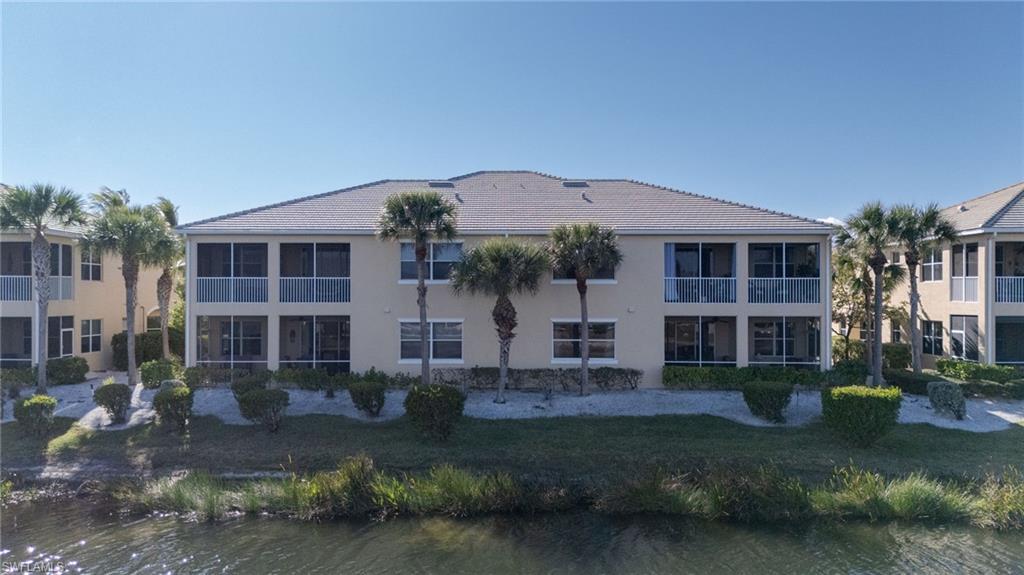 Two-story stucco structure with multiple screened patios, a tiled roof, and established landscaping