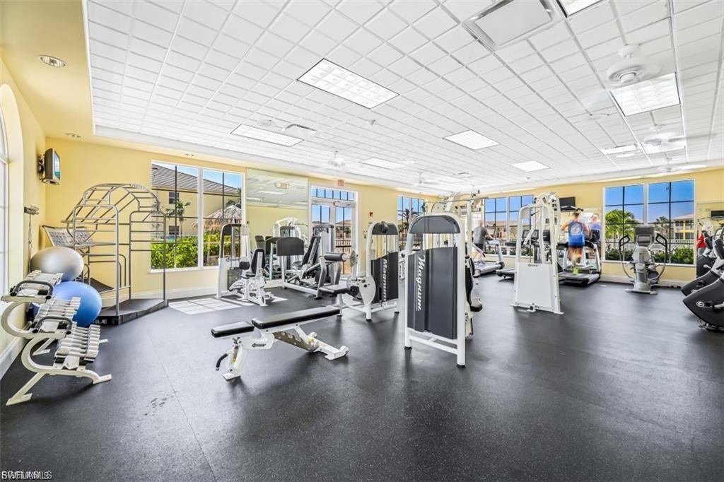 Spacious fitness center featuring various exercise equipment, large windows, recessed lighting, ceiling fans, and durable rubber flooring