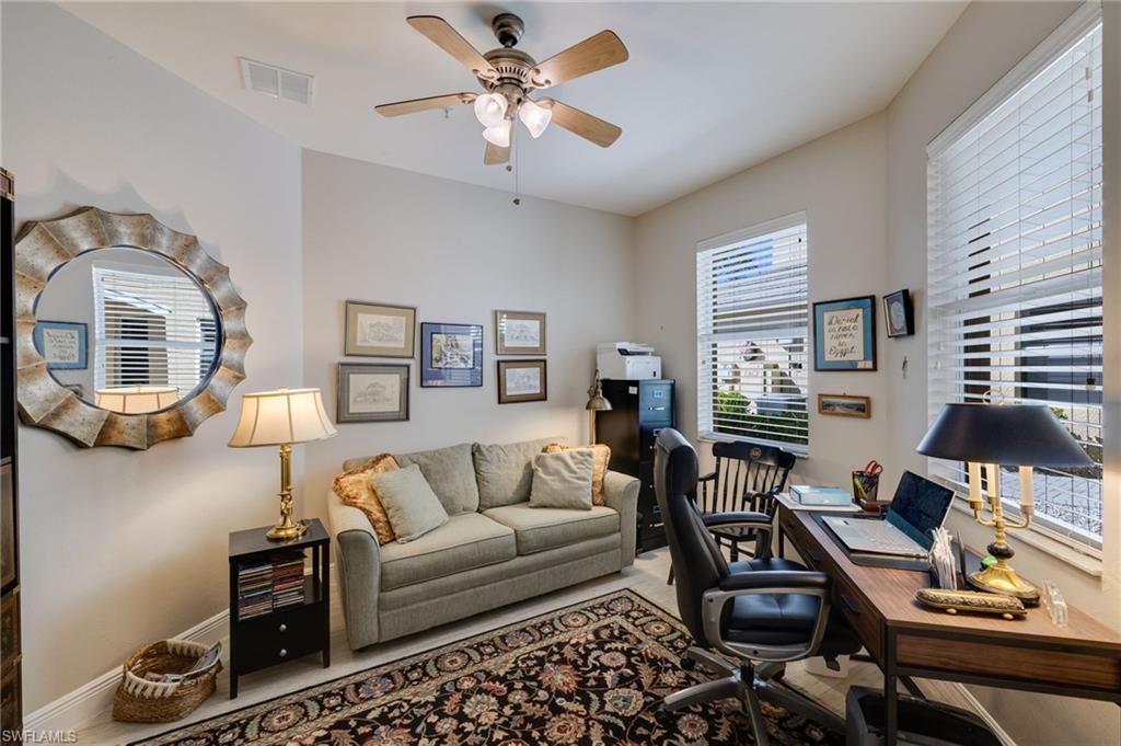 Spacious room featuring multiple windows with blinds, wood-finish flooring, and a ceiling fan with integrated lighting