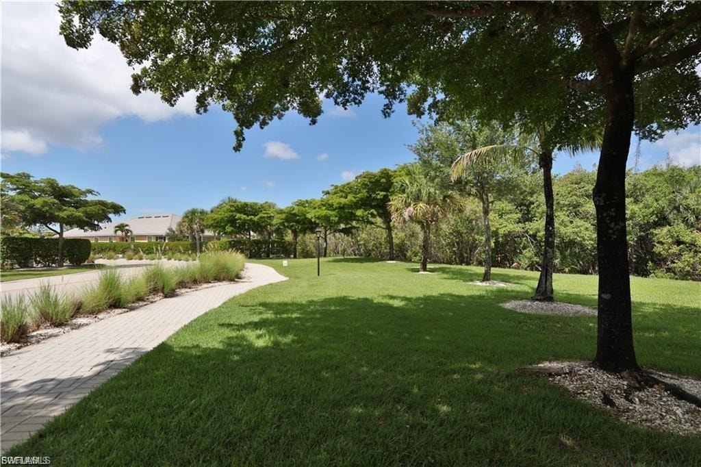 Manicured lawn with mature trees and a paved walkway