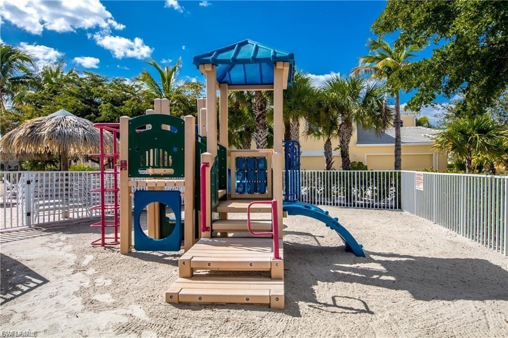 Playground structure featuring a slide, ladder, and multiple activity panels on a sand-covered ground