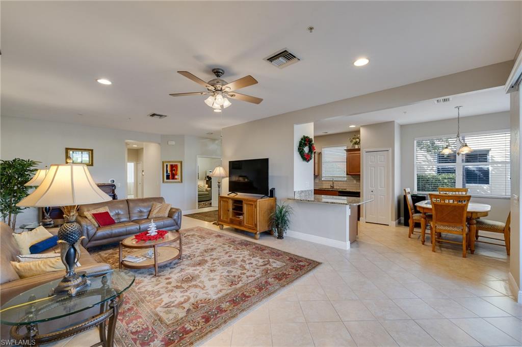 Open-concept living area with tile flooring, recessed lighting, ceiling fan, and a kitchen pass-through with counter seating