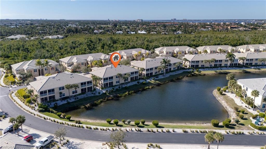 Waterfront community setting with mature landscaping, a paved road, and a distant city skyline