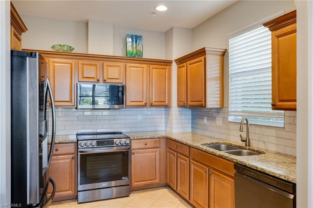 Kitchen featuring wood cabinetry with crown molding, light-toned countertops, a subway tile backsplash, and stainless steel appliances