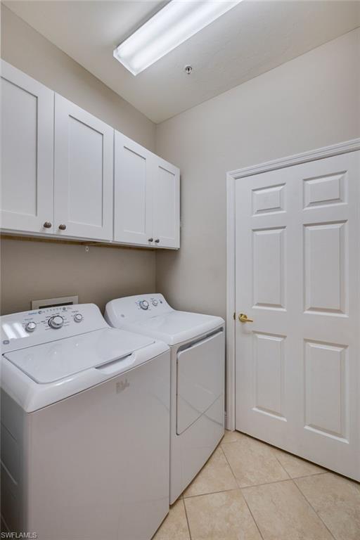 White shaker-style cabinetry, tiled flooring, overhead strip lighting, paneled interior door, and a brass door handle