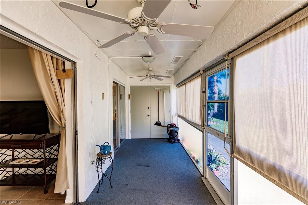 Enclosed sunroom featuring multiple ceiling fans, carpeted flooring, and sliding glass panel windows with privacy shades