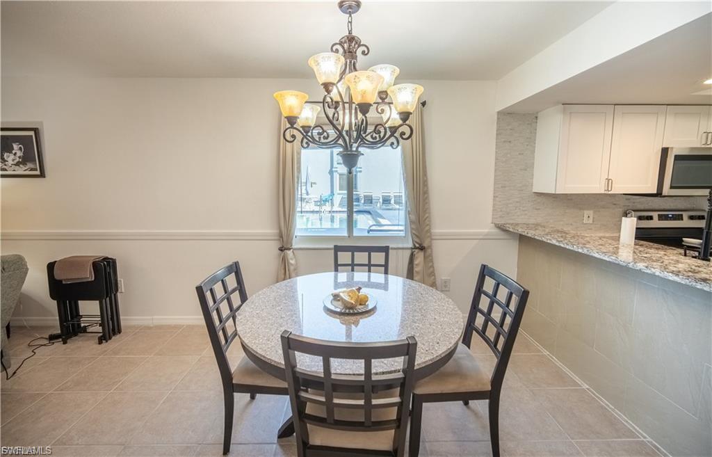 Dining area featuring a central chandelier, tiled flooring, and chair rail molding