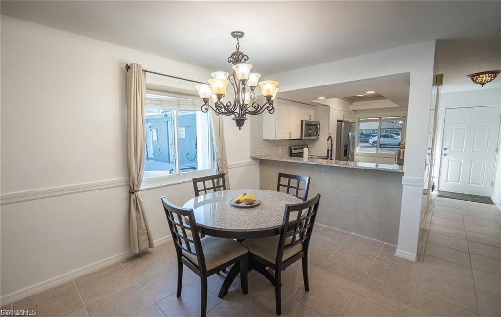 Dining area featuring a contemporary chandelier, tile flooring, and a window with natural light