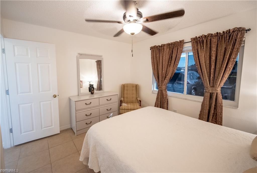 Bedroom featuring tile flooring, a multi-pane window, and a ceiling fan with integrated lighting