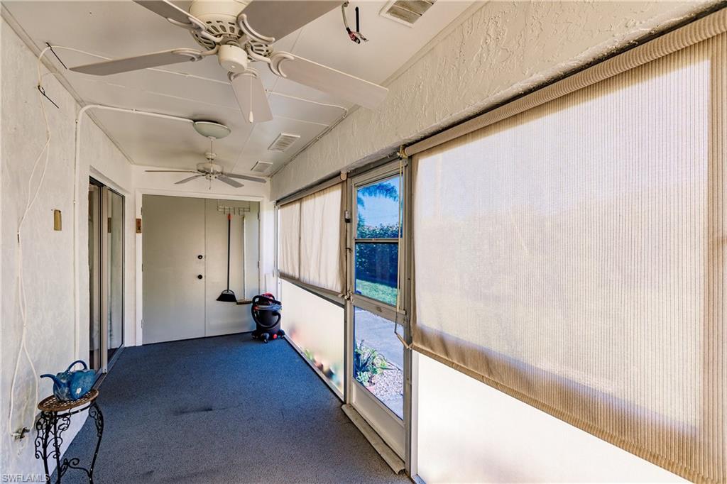 Enclosed patio featuring textured white walls, a gray carpeted floor, multiple ceiling fans, and roller shades on the windows