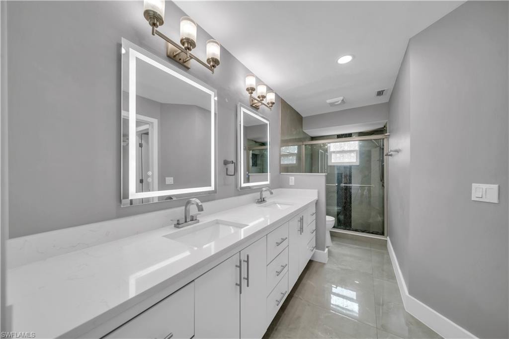 Dual vanity with integrated sinks, frameless backlit mirrors, and brushed nickel fixtures