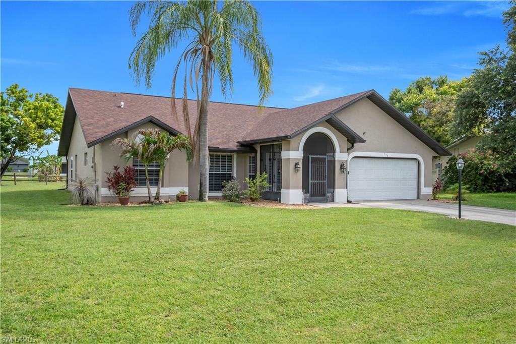 Stucco exterior with a brown shingle roof, arched entryway, and an attached two-car garage