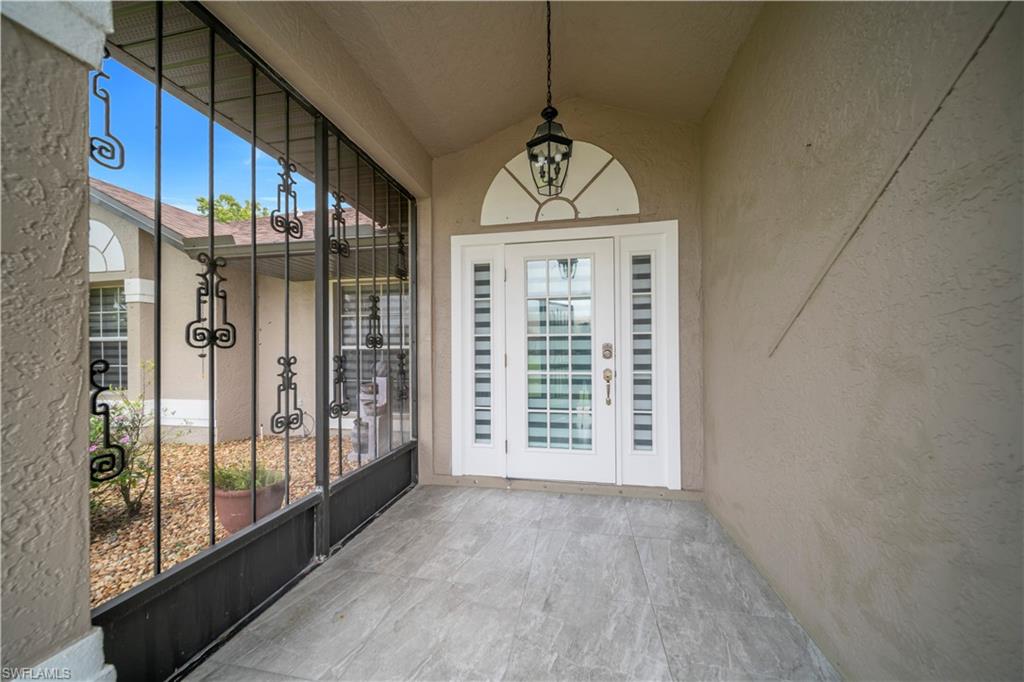 Screened entry porch with decorative ironwork, textured exterior walls, and a tiled floor