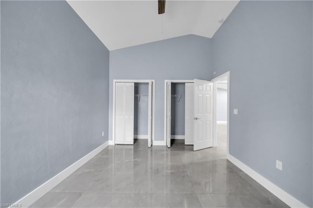 Vaulted ceiling, two bi-fold closet doors, tile flooring, and a six-panel interior door