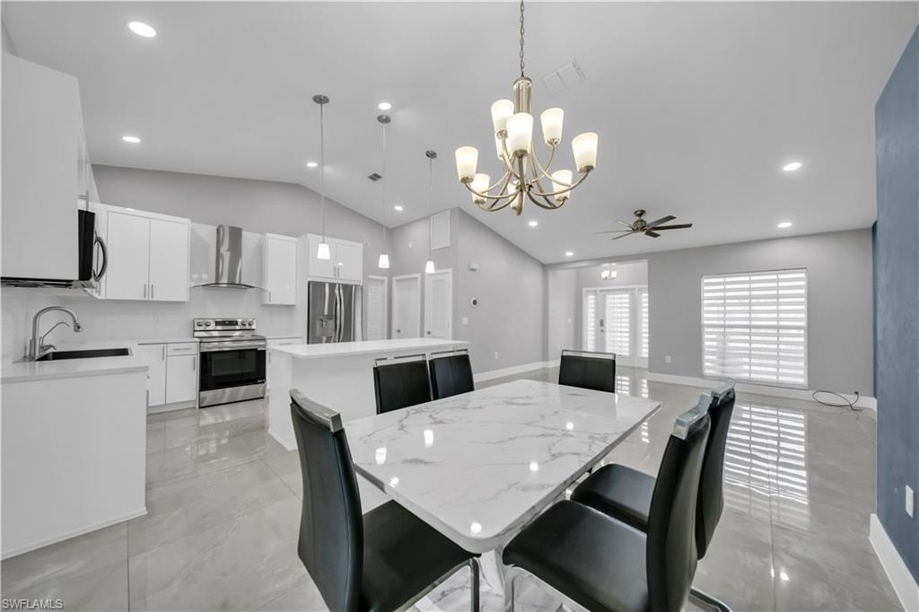 Modern kitchen featuring white cabinetry, stainless steel appliances, a center island with pendant lighting, and tile flooring