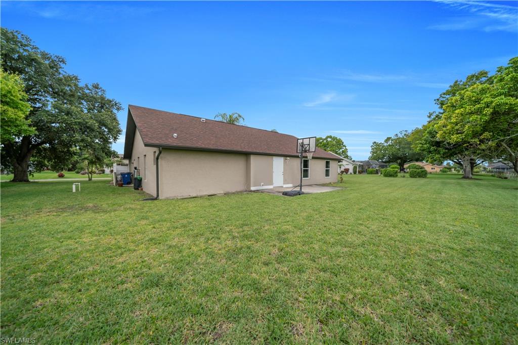 Expansive green lawn bordering the property, with mature trees providing natural shading