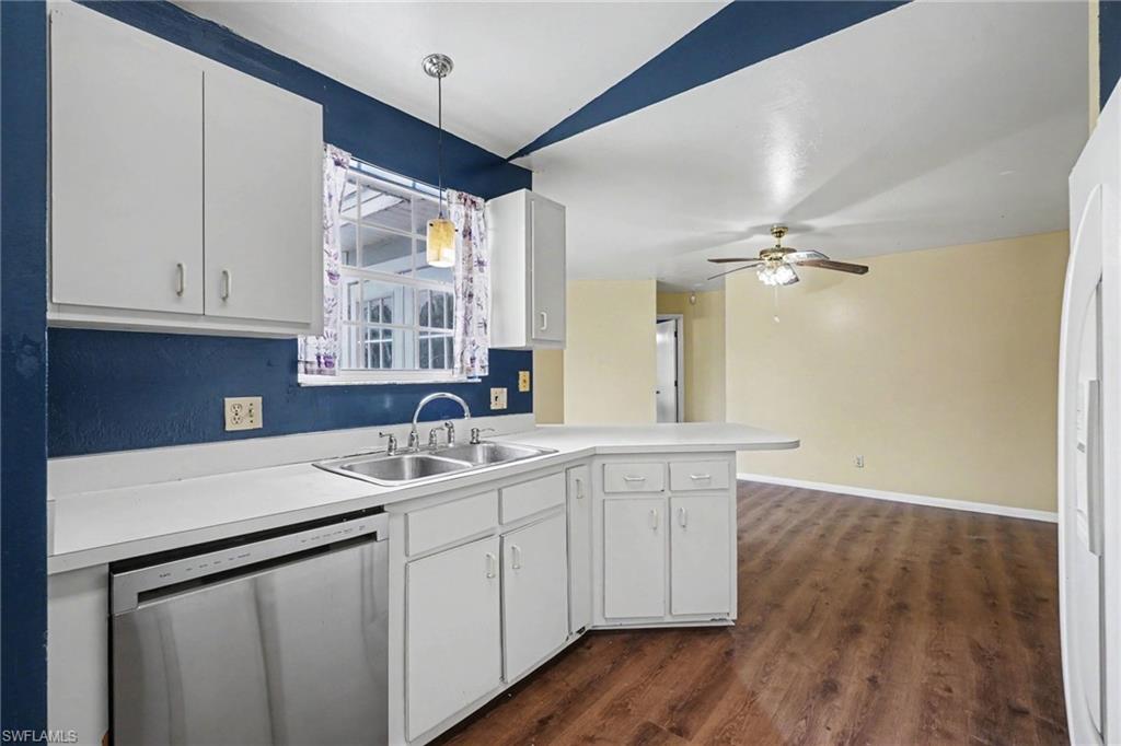 Kitchen area featuring white cabinetry, a double basin stainless steel sink, and white countertops