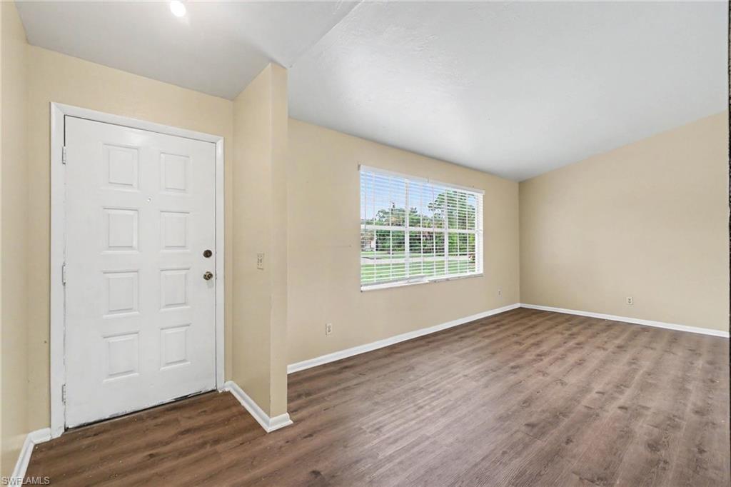 Entry area featuring wood-finish flooring, a paneled entry door with circular hardware, and a large window with horizontal blinds