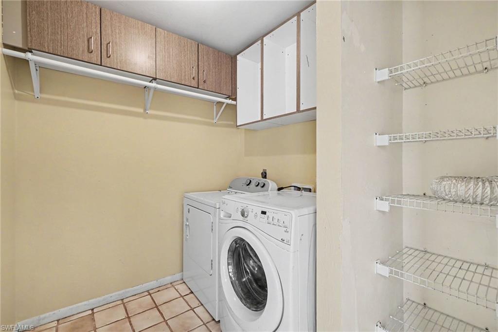 Laundry area featuring tile flooring, wood-finish upper cabinetry, and wire shelving