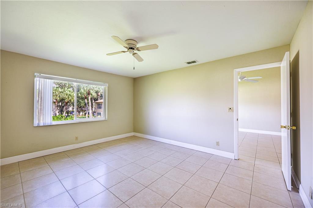 Tile flooring throughout with a ceiling fan and a window overlooking lush landscaping