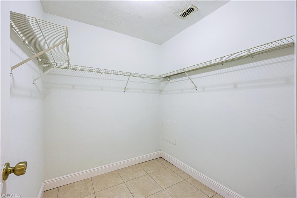 Walk-in closet featuring wire shelving, tile flooring, and base molding
