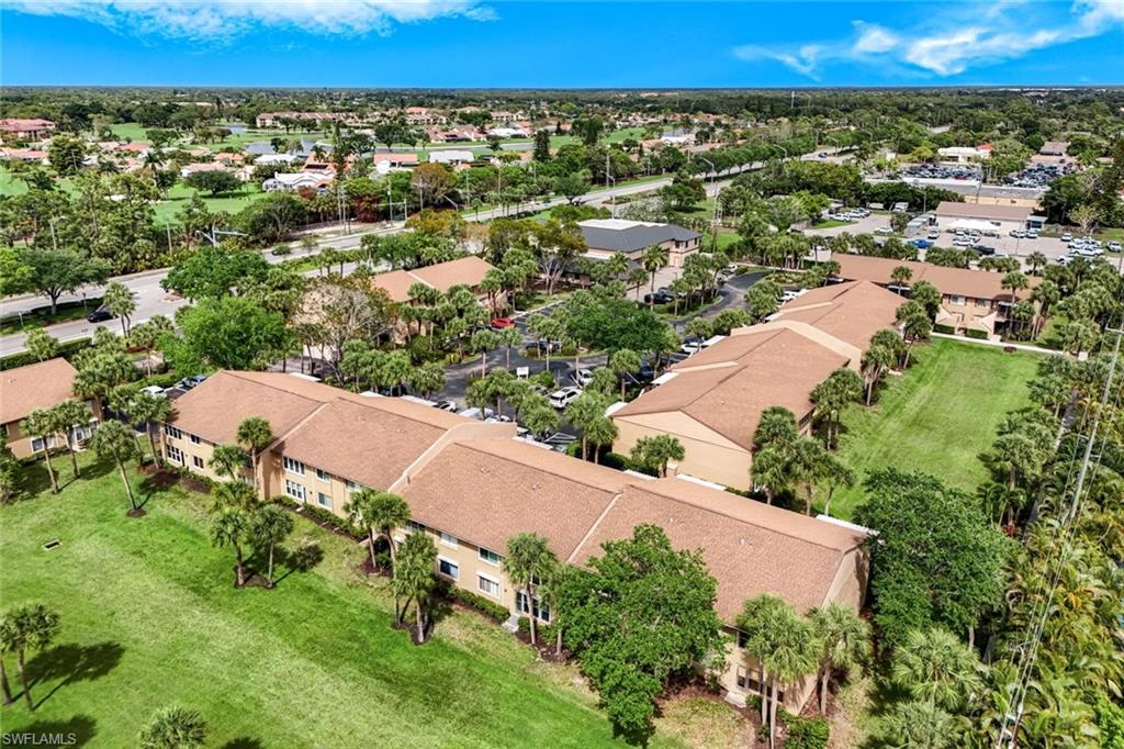 Expansive aerial view showcasing this residence set on manicured grounds with mature palms and lush landscaping