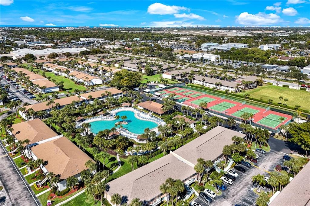 Expansive community featuring multiple residential buildings, a large central swimming pool, and dedicated tennis courts