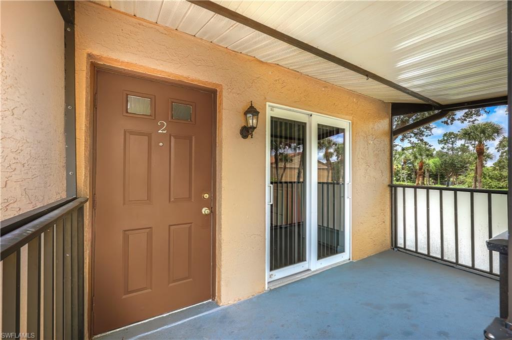 Covered entry porch featuring a paneled door with upper glass inserts, exterior wall sconce, and textured stucco finish